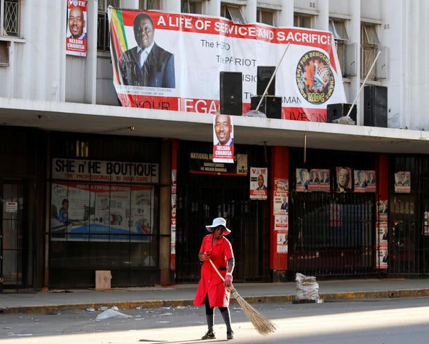 A woman sweeps the street outside the opposition Movement for Democratic Change (MDC) headquarters in Harare