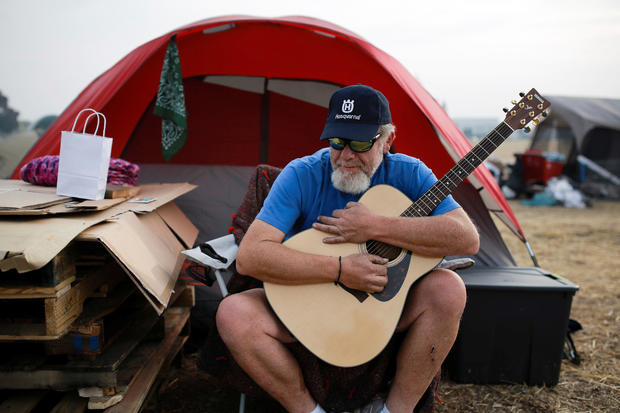 Kelly Boyer plays a guitar he was given outside his tent near a Walmart in Chico, California, after the Camp Fire destroyed his home in Paradise, Nov. 20, 2018. 