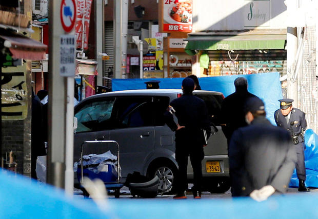 Police officers stand next to a car that plowed into pedestrians in Tokyo, Japan, Jan. 1, 2019. 