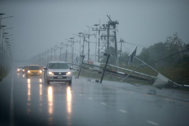 Cars and fallen electricity poles are seen along a road as tropical storm Pabuk approaches the southern province of Nakhon Si Thammarat