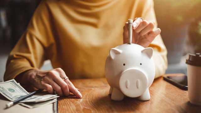 woman hand putting money bank note dollar into piggy for saving money wealth and financial concept. 