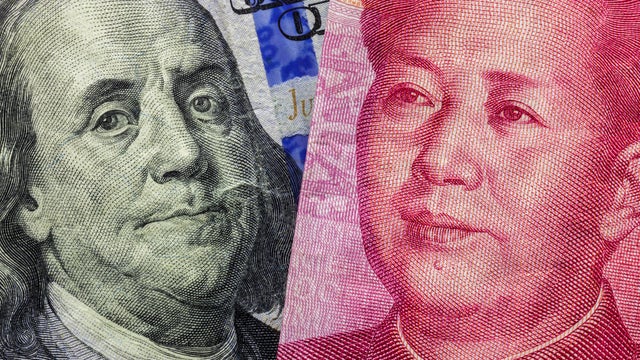 Close up of one hundred Dollar and 100 Yaun banknotes with focus on portraits of Benjamin Franklin and Mao Tse-tung/USA vs China trade war concept