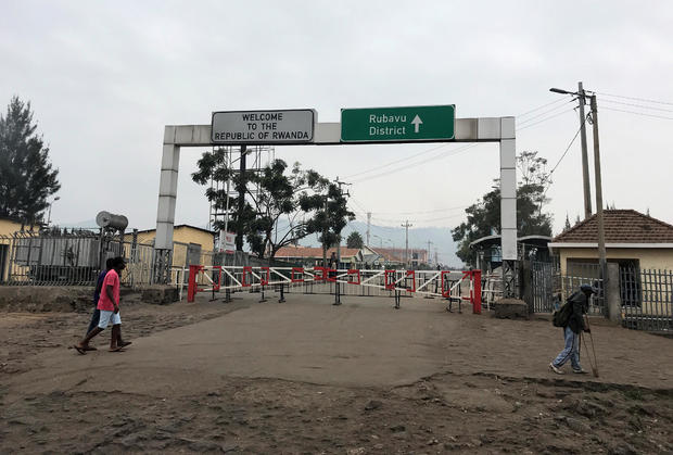 Congolese people walk near the gate barriers at the border crossing point with Rwanda following its closure over Ebola threat in Goma 