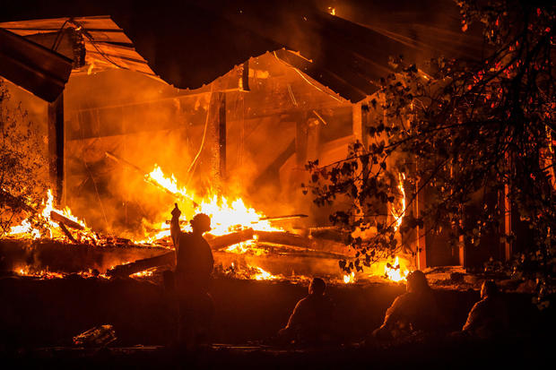 Firefighters look on as a structure burns in the Kincade fire off Highway 128, east of Healdsburg, California, on October 29, 2019. 