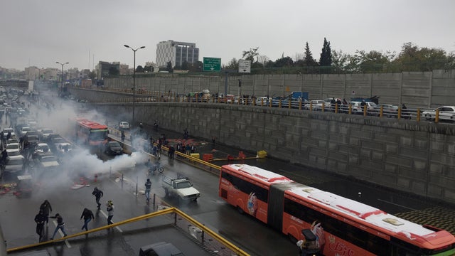Riot police tries to disperse people as they protest on a highway against increased gas price in Tehran
