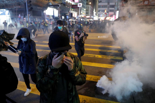 Anti-government protesters react to tear gas during a protest on Christmas Eve at Tsim Sha Tsui in Hong Kong 