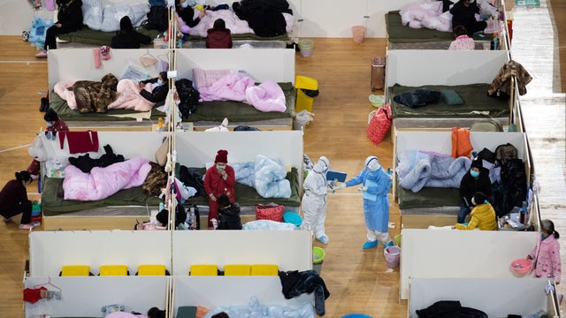 Medical personnel are seen walking among patients with mild symptoms of coronavirus resting at night in a temporary hospital set up in a sports stadium in Wuhan, China, February 18, 2020.