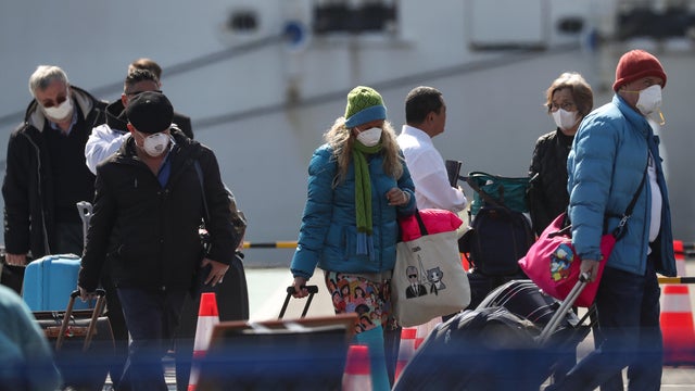 Passengers wearing masks leave cruise ship Diamond Princess at Daikoku Pier Cruise Terminal in Yokohama