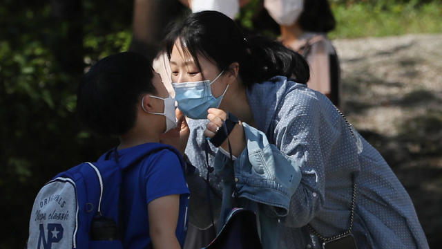 A mother kisses her child as they both wear masks to avoid the spread of the coronavirus disease (COVID-19) at an elementary school in Seoul 