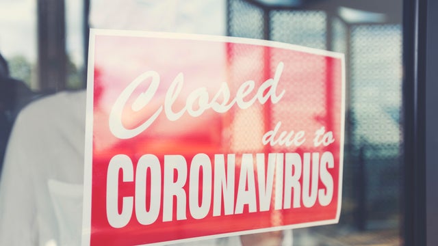 Store owner putting up a closed sign in the window