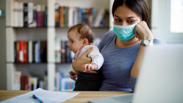 Cropped shot of a young Asian mother using laptop and working from home while taking care of little daughter in self isolation during the Covid-19 health crisis