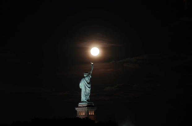 The Harvest Moon Rises Behind the Statue of Liberty in New York City 