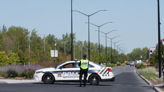 Police officers block a street leading to a condo building in Longueil 