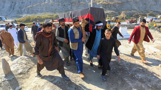 Afghan men carry the coffin of one of three female media workers who were shot and killed by unknown gunmen, in Jalalabad 