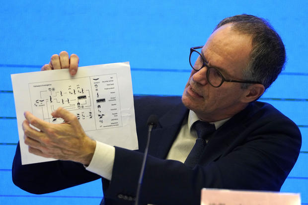 Peter Ben Embarek of the World Health Organization holds up a chart showing pathways of transmission of the coronavirus during a joint news conference at the end of a mission in Wuhan in central China's Hubei province February 9, 2021. 