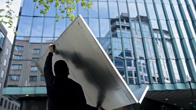 Worker carries HVAC into a building 