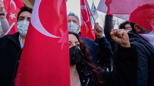 A protester makes a gesture while holding a Turkish flag in 