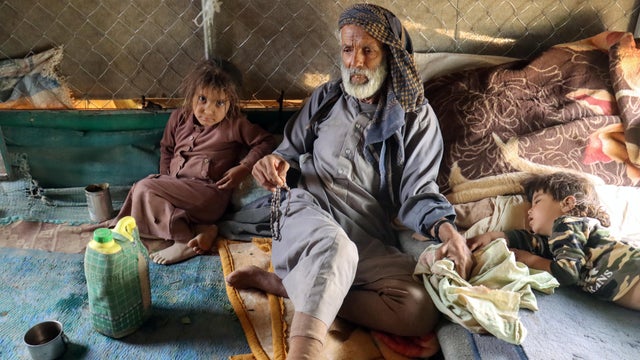 Ali al-Nehmi, 70, sits with his grandchildren in their hut at a camp for internally displaced people (IDPs) in Marib