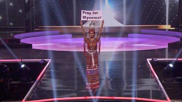 Ma Thuzar Wint Lwin, Miss Universe Myanmar, holds the "Pray for Myanmar" sign during Miss Universe pageant's national costume show, in Hollywood 