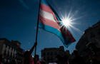 Demonstrator waving the Trans flag attends a protest where 