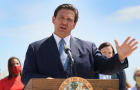 Florida Governor, Ron DeSantis listens to another speaker at 