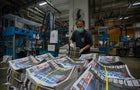An employee stacks freshly printed papers onto a pallet in 