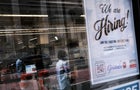 "We are hiring" sign in store window 