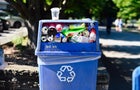 Blue plastic recycling bin full of bottles and cans 