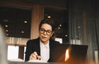 Low angle view of serious female financial advisor reading book at table in law office 