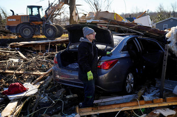 Jeremiah Barker, 37, stands by his destroyed car while looking out at the pile of debris where his home once stood in the aftermath of a tornado in Mayfield, Kentucky, December 13, 2021. 