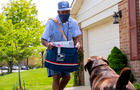 Annapolis Letter Carrier Thomas Tyler delivering to a house with dog. 