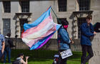 A protester holds a Trans Pride flag and a 'Protect Trans 