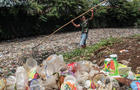 A man nets plastic waste to let water flow in the Bojong 