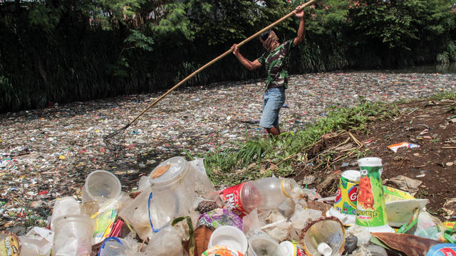 A man nets plastic waste to let water flow in the Bojong 