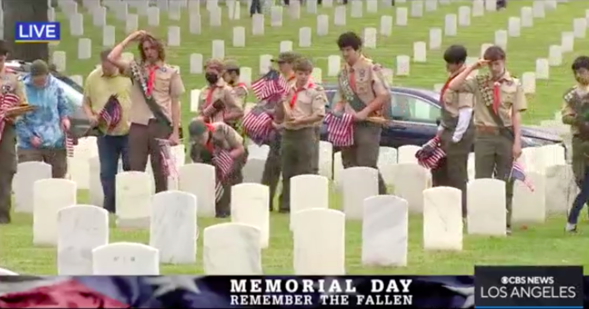 Scouts place flags at the graves of fallen military members for Memorial Day